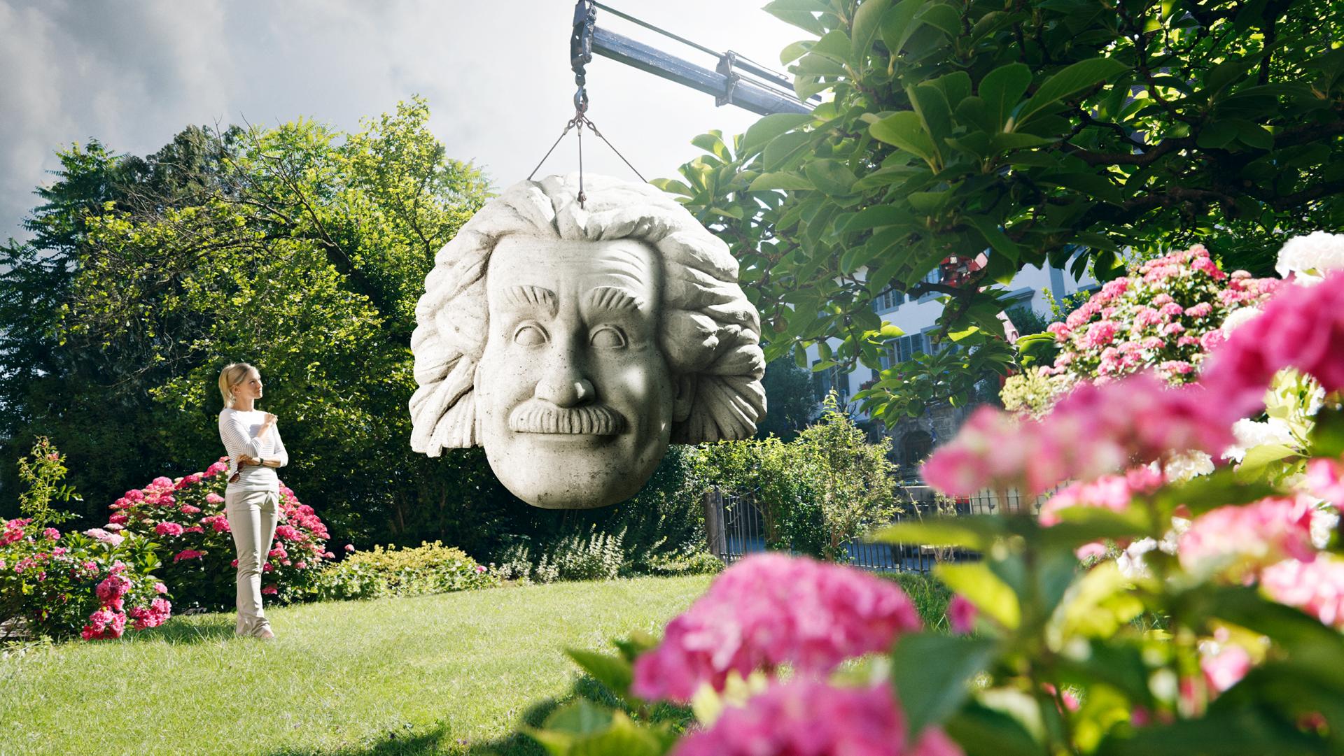 Keyvisual Creabeton Materiaux: Ein grosser Albert Einstein Betonkopf wird in den Garten einer Frau gestellt