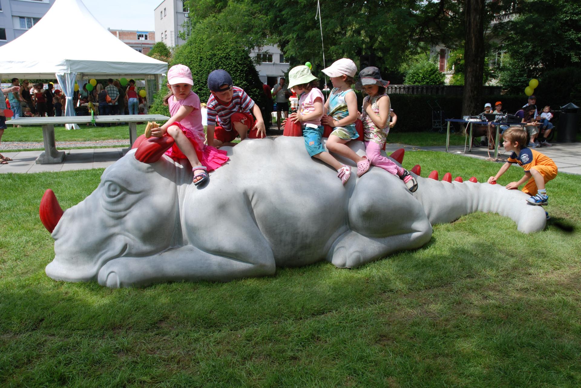 Soziales Engagement: Kinder spielen auf einem Beton-Dinosaurier