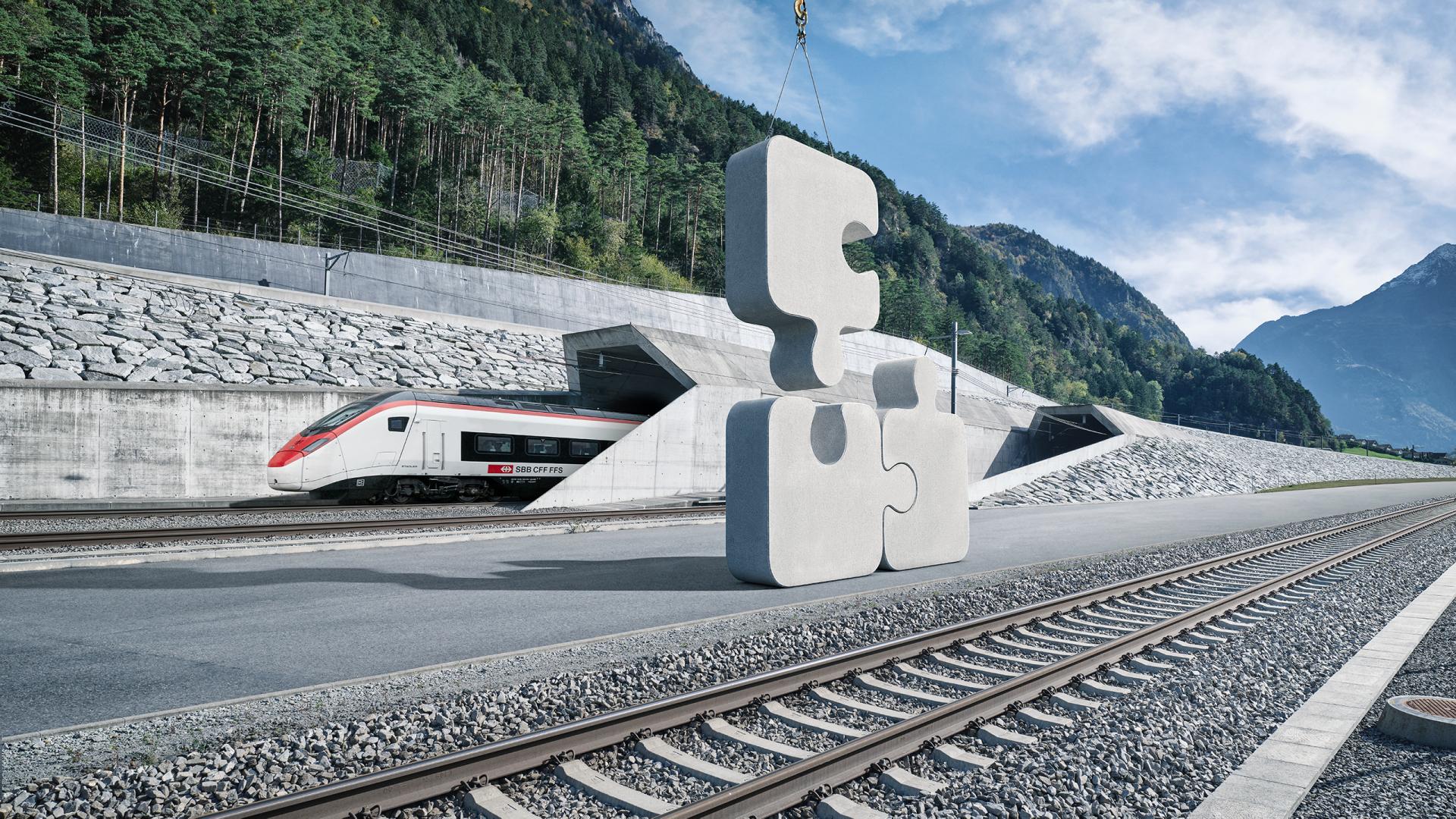 Vigier Rail Keyvisual: Ein Beton-Puzzle, das auf einem Bahnsteig steht. Das dritte Puzzleteil wird von einem Kran angefügt.